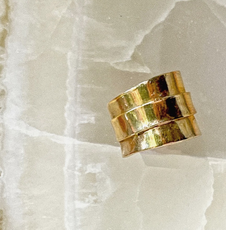 A three stepped gold ear cuff on a slab of onyx.
